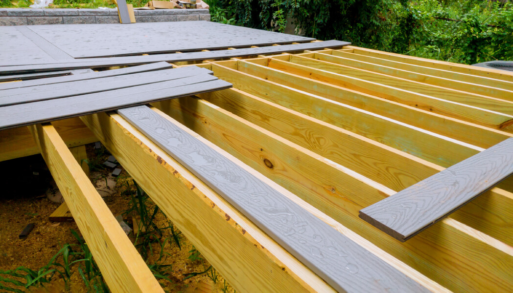 New construction is shown, with a wooden frame and composite planks, on a sunny day.